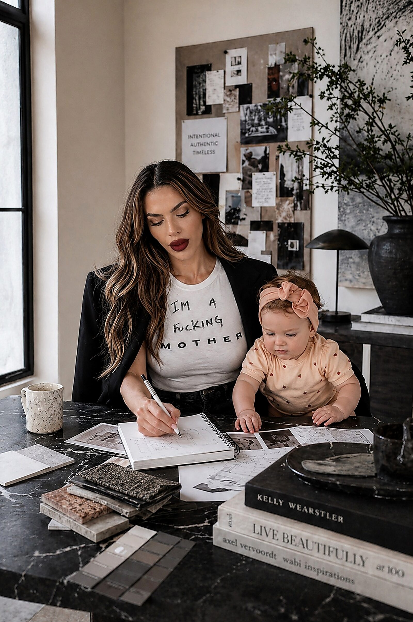 Andrea working at her studio desk with her daughter